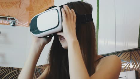 Girl-sitting-in-bathroom-looking-in-virtual-reality-glasses.-Modern-gadget