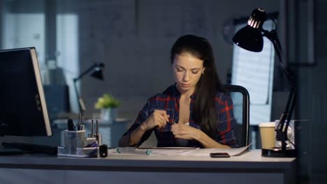 En-la-tarde-noche-oficina-mujer-diseño-Ingeniero-de-proyectos-con-la-ayuda-de-reglas-y-el-desarrollo.-Trabajo-de-colegas-en-el-fondo.