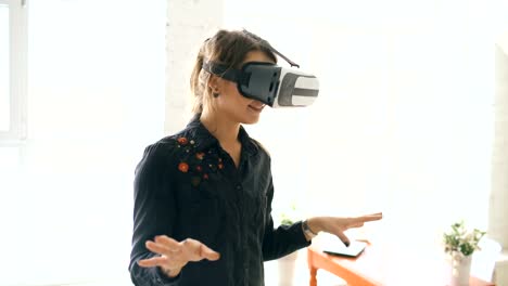 Frau-in-VR-Kopfhörer-nachschlagen-und-versucht,-tippen-Sie-auf-Objekte-in-der-virtuellen-Realität-zu-Hause-drinnen