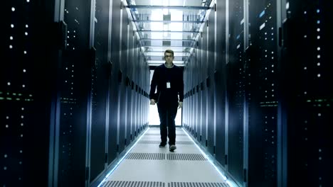 Frontal-View-of-IT-Engineer-Walking-Through-Data-Center-with-Working-Rack-Servers.
