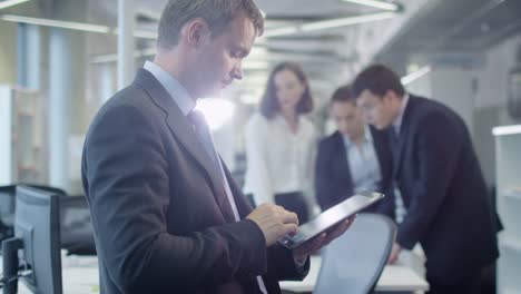 Businessman-Working-on-Tablet-in-Crowded-Office