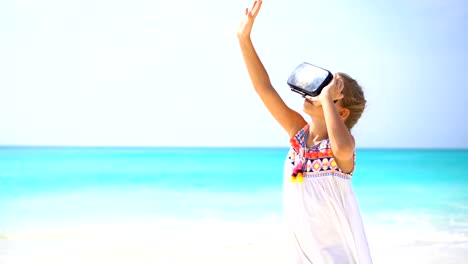 Cute-little-child-girl-using-VR-virtual-reality-goggles.-Adorable-girl-look-into-the-virtual-glasses-on-white-beach