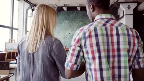 Two-colleagues-walking-through-and-discussing-the-documents.-Caucasian-woman-and-african-man-working-at-modern-office