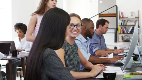 Three-women-working-together-at-computer-in-open-plan-office