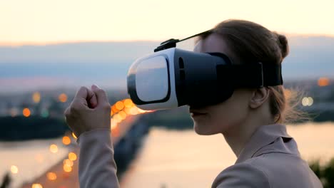 Woman-uses-virtual-reality-glasses-in-the-city-after-sunset