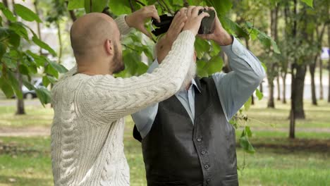 Grandson-with-grandfather-uses-a-virtual-reality-glasses-in-park