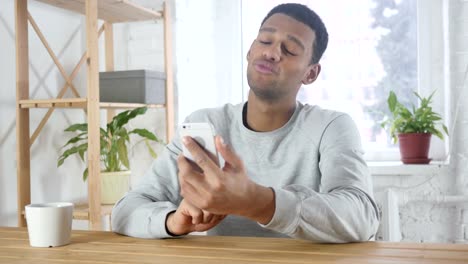 Smartphone-Video-Chat-by-Young-Afro-American-Man-in-Office