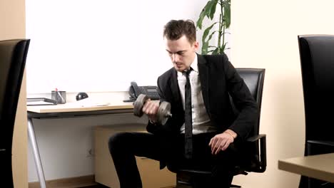 Work-out-in-the-office,-man-in-a-suit-does-an-exercise-for-the-biceps-while-sitting-in-the-office.-60-fps