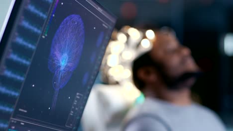 In-Laboratory-Man-Wearing-Brainwave-Scanning-Headset-Sits-in-a-Chair-with-Closed-Eyes.-Monitors-Show-EEG-Reading-and-Graphical-Brain-Model.-In-the-Modern-Brain-Study/-Neurological-Research-Laboratory.