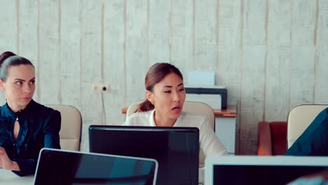 Asian-girl-behind-laptops-in-the-office-communicates-with-colleagues,-they-team-discuss-business-ideas