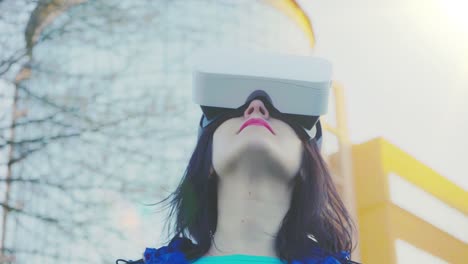 Young-woman-wearing-VR-glasses,-headset,-playing-virtual-games-and-watching-videos-outdoors-against-the-background-of-a-glass-building