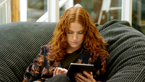 Businesswoman-sitting-on-the-armchair-and-using-digital-tablet-4k