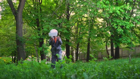 Child-in-VR-glasses-runs-across-the-grass-and-catches-something,-child-have-fun-experiencing-3D-gadget-technology