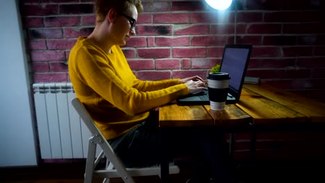 Atractivo-joven-trabajando-en-el-escritorio-con-un-ordenador-portátil-en-la-oficina-en-casa.