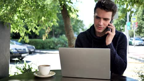 Mann-Reden-am-Telefon-während-der-Arbeit-am-Laptop-im-Cafe-Terrasse