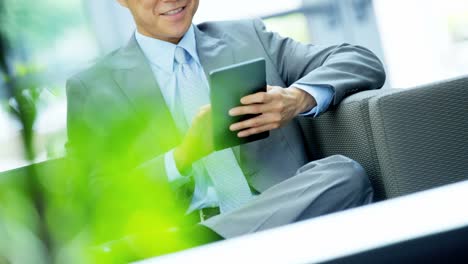 Asian-American-businessman-in-office-atrium-with-tablet