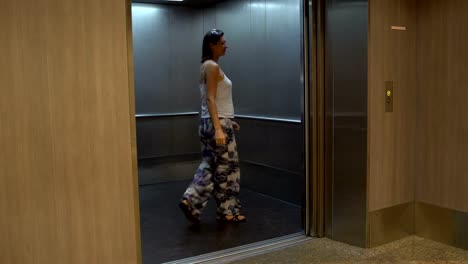 Eine-Frau-betritt-den-Aufzug-und-die-Tür-schließt
