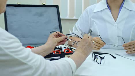 Woman-Choosing-New-Eyeglasses-with-Help-of-Doctor