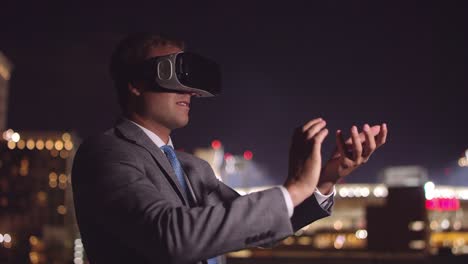 Young-business-man-wearing-VR-headset-at-night-creating-ball-with-hand-gestures