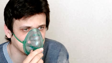 Verwenden-Sie-Vernebler-und-Inhalator-für-die-Behandlung.-Junger-Mann-durch-Inhalator-Maske-Einatmen.-Seitenansicht.