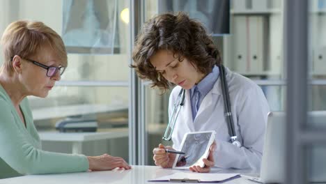 Frau-Doktor-zeigen-Röntgenbild-auf-Tablet,-Senior-Woman