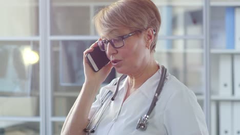 Mediana-edad-Doctor-mujer-hablando-por-teléfono-celular