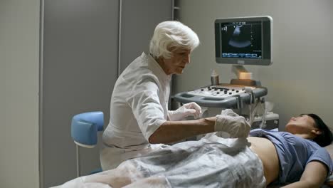 Senior-Female-Doctor-Performing-Ultrasound-Exam