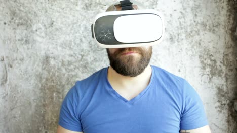 Bearded-man-uses-VR-headset-display-with-headphones-for-virtual-reality-game.