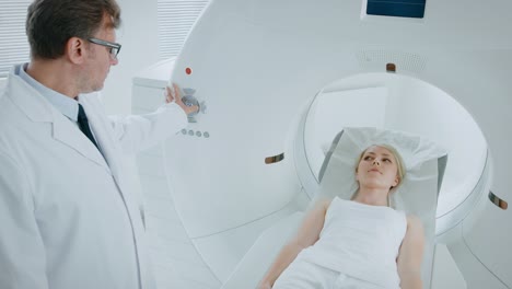 Im-medizinischen-Labor-kontrolliert-männlichen-Radiologe-MRT-oder-CT-oder-PET-Scan-mit-weiblichen-Patienten-unterziehen-Verfahren.-High-Tech-moderne-Medizintechnik.-Erhöhte-Kameraeinstellung.