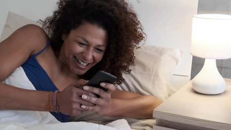 One-black-woman-texting-on-mobile-phone-in-bed