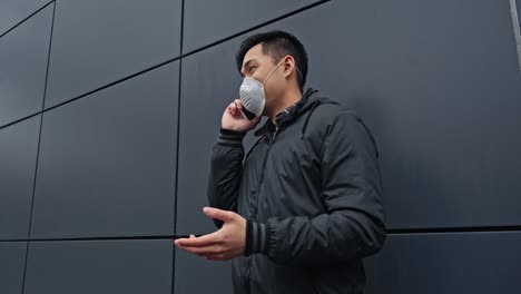 asian-man-in-medical-mask-talking-on-smartphone