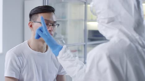 Doctor-in-Disposable-Coveralls-Doing-Neurological-Exam-on-Patient