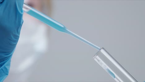 Techniker-tropft-die-Lösung-sorgfältig-aus-der-Pipette-in-Glasröhren.