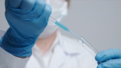 Technician-carefully-drips-the-solution-from-the-pipette-into-glass-tubes.