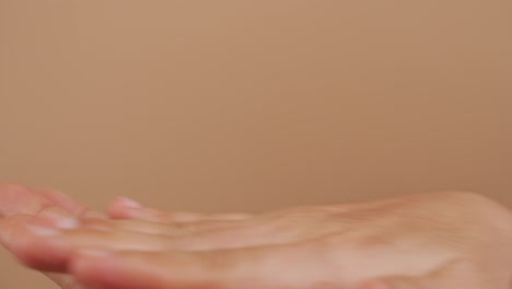 Close-up-shot-of-woman-'s-hands-putting-hand-sanitizer-on-hands-for-washing-her-hands-isolated-over-beige-background.-4K-video