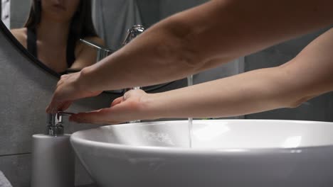 Händewaschen,-um-coronavirus-Covid-19-Infektion-zu-verhindern.-Frau-wähbe-Hände-mit-Seife-in-Waschbecken-im-modernen-Bad.-Weibchen-ist-waschen-und-schäumen-Hände-mit-Schaum,-reiben-Finger,-um-die-Haut-zu-waschen