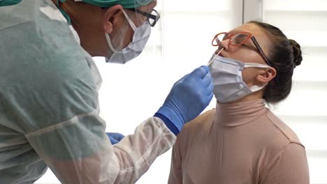 Lab-technician-in-a-protective-suit-takes-a-swab-from-an-female-patient-for-coronavirus