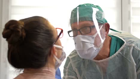 Mujer-Paciente-que-se-prueba-con-un-hisopo-bucal-para-coronavirus-por-un-trabajador-médico-vestido-con-un-traje-de-hazmat,-gafas-protectoras-y-una-máscara-facial