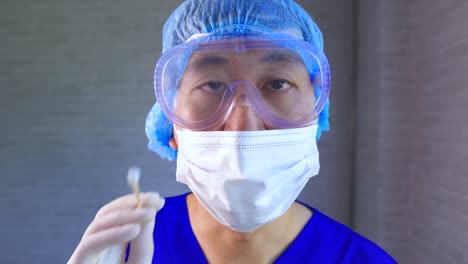 Asiatische-männliche-medizinische-Arbeiter-in-Ppe-Uniform-und-Gesichtsmaske-arbeiten-im-Krankenhaus-Diagnose-und-Untersuchung-Covid-19-Patienten.-Junge-Krankenschwester,-die-eine-Nasenabstrichprobe-nimmt,-um-auf-Corona-Virus-Infektion-zu-testen