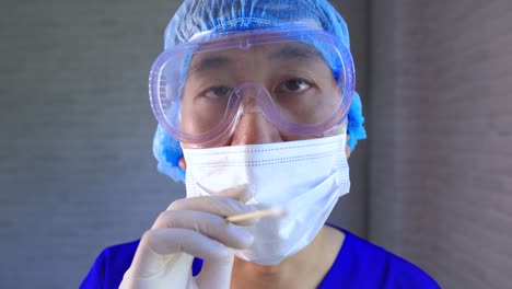 Asiatische-männliche-medizinische-Arbeiter-in-Ppe-Uniform-und-Gesichtsmaske-arbeiten-im-Krankenhaus-Diagnose-und-Untersuchung-Covid-19-Patienten.-Junge-Krankenschwester,-die-eine-Nasenabstrichprobe-nimmt,-um-auf-Corona-Virus-Infektion-zu-testen