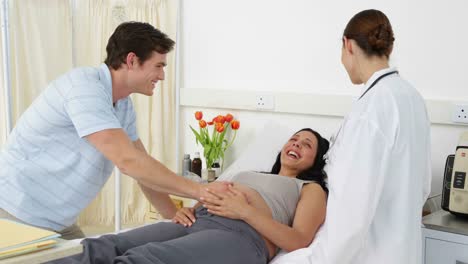 Pregnant-woman-lying-on-bed-talking-with-partner-and-doctor