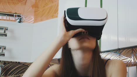 Girl-sitting-in-bathroom-with-virtual-reality-mask-on-head.-Looking-around