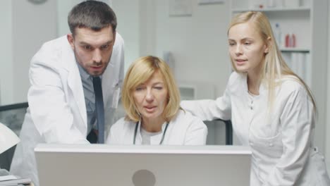 Personal-médico-discutir-problemas-relacionados-con-el-trabajo-durante-el-uso-de-ordenador-personal.-Male-doctor-Points-en-la-pantalla.-Ellos-asienten-de-acuerdo.