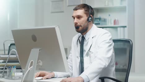 Male-Doctor-Consults-Patients-on-the-Internet.-He-Sits-before-His-Personal-Computer-and-Wears-Microphone.