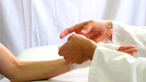 Physiotherapeuten,-die-Bandage-anziehen-an-der-Hand-des-Patienten-verletzt