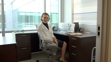 Portrait-Of-Female-Doctor-Working-At-Desk-In-Office