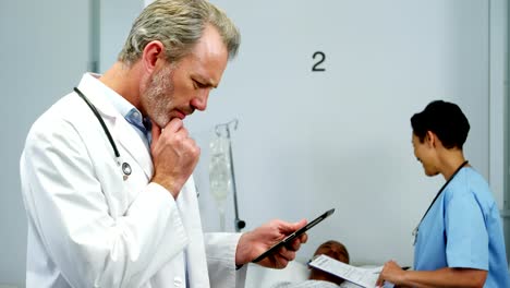 Doctor-using-digital-tablet-while-nurse-interacting-with-patient