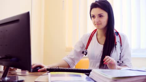 Joven-mujer-médico-con-estetoscopio-sentado-en-la-mesa-cerca-de-la-ventana-y-escribiendo