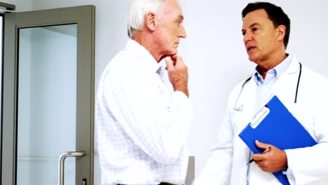 Male-doctor-interacting-with-male-senior-man-in-the-passageway