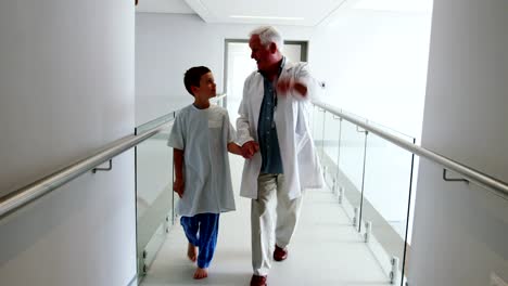 Doctor-interacting-with-patient-while-walking-in-corridor